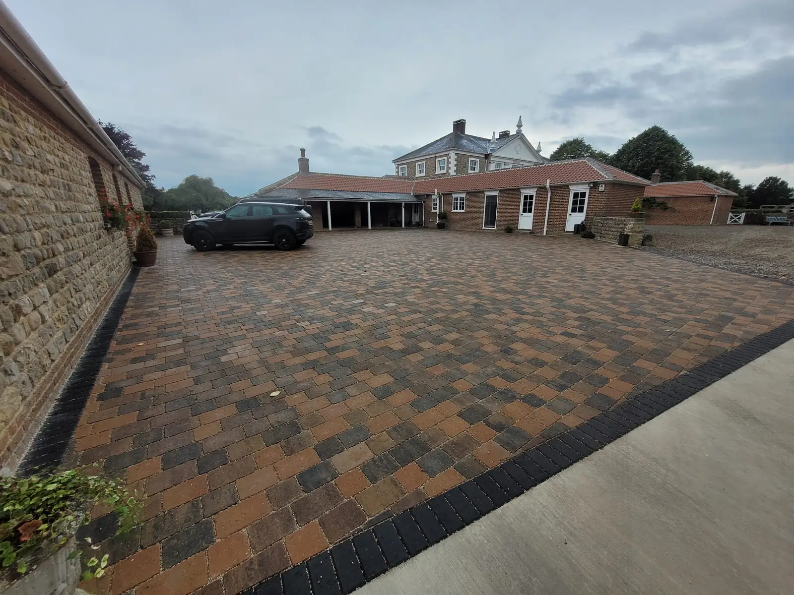 Block paved courtyard beside a stone house