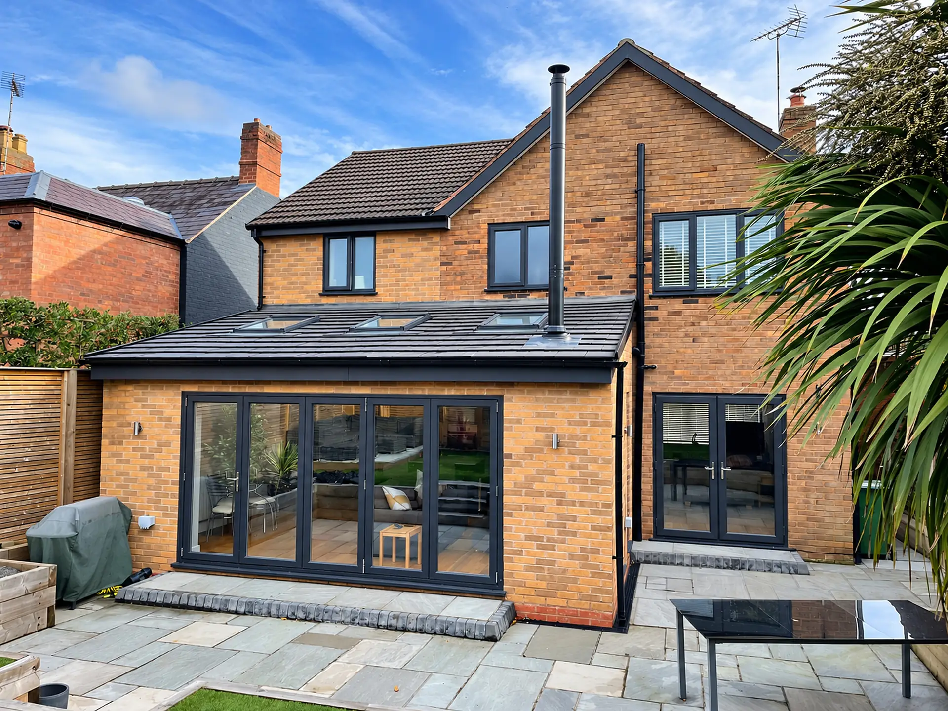 Brick rear extension with bifold doors and a sandstone patio