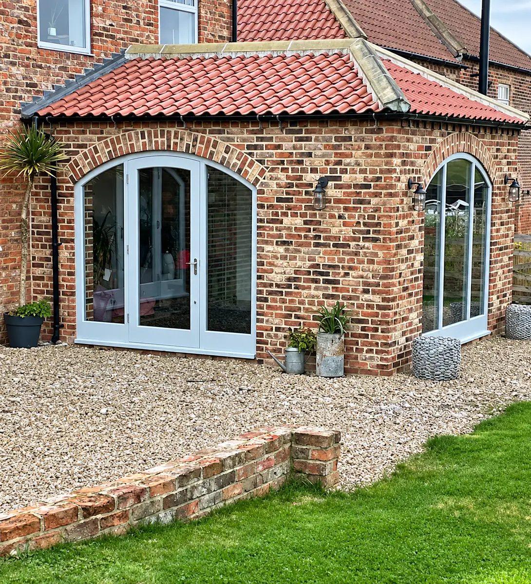 Brick orangery with arched glazed doors and a pantile roof