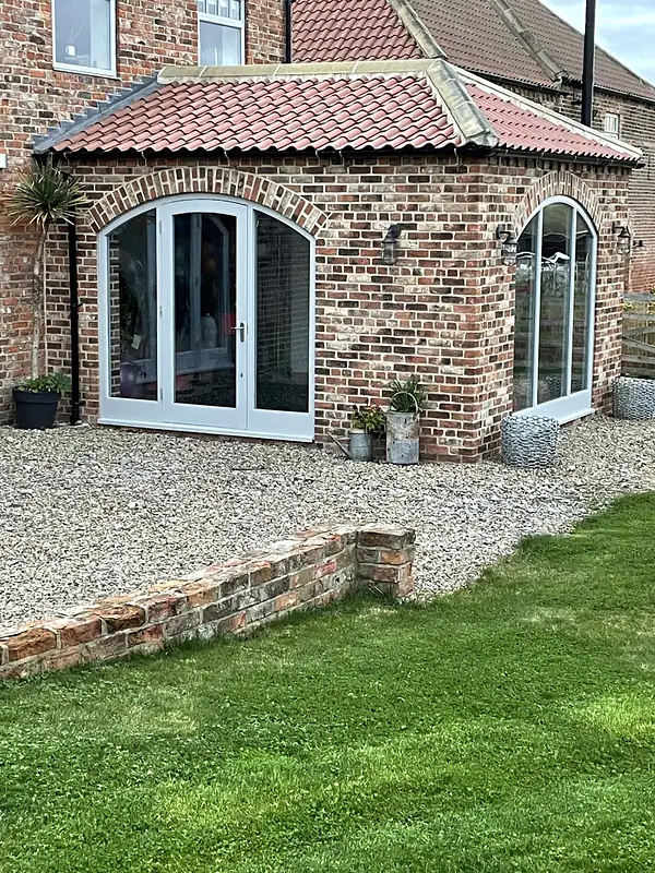 Converted brick barn with arched glazed doors
