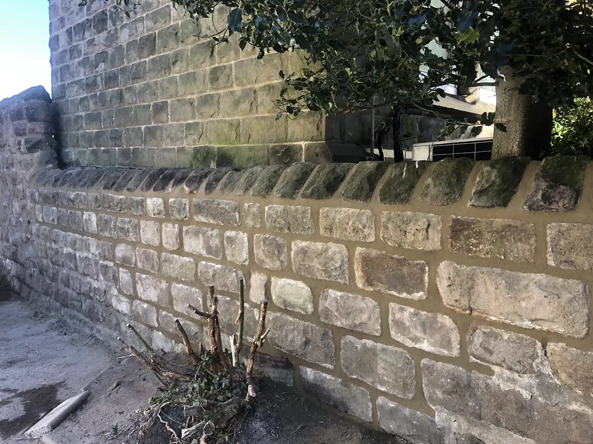 Coped stone wall rebuilt in the original stone
