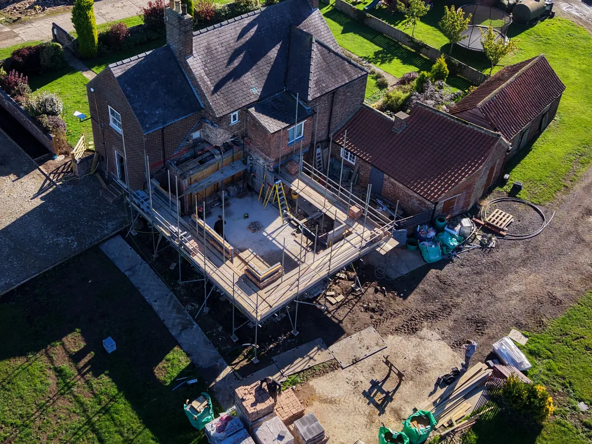 A farmhouse, yard and outbuildings seen from the drone