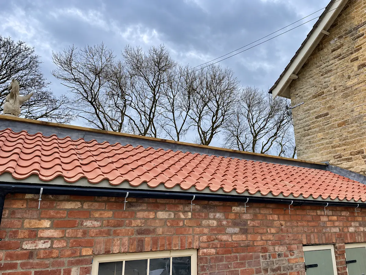 New pantile roof on a brick building beside a stone house