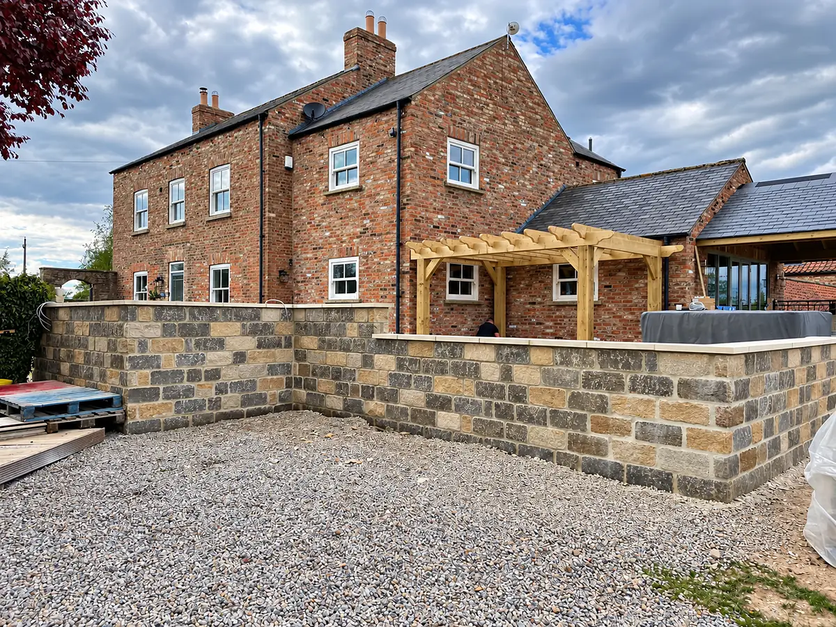 New sandstone garden wall in front of a brick house