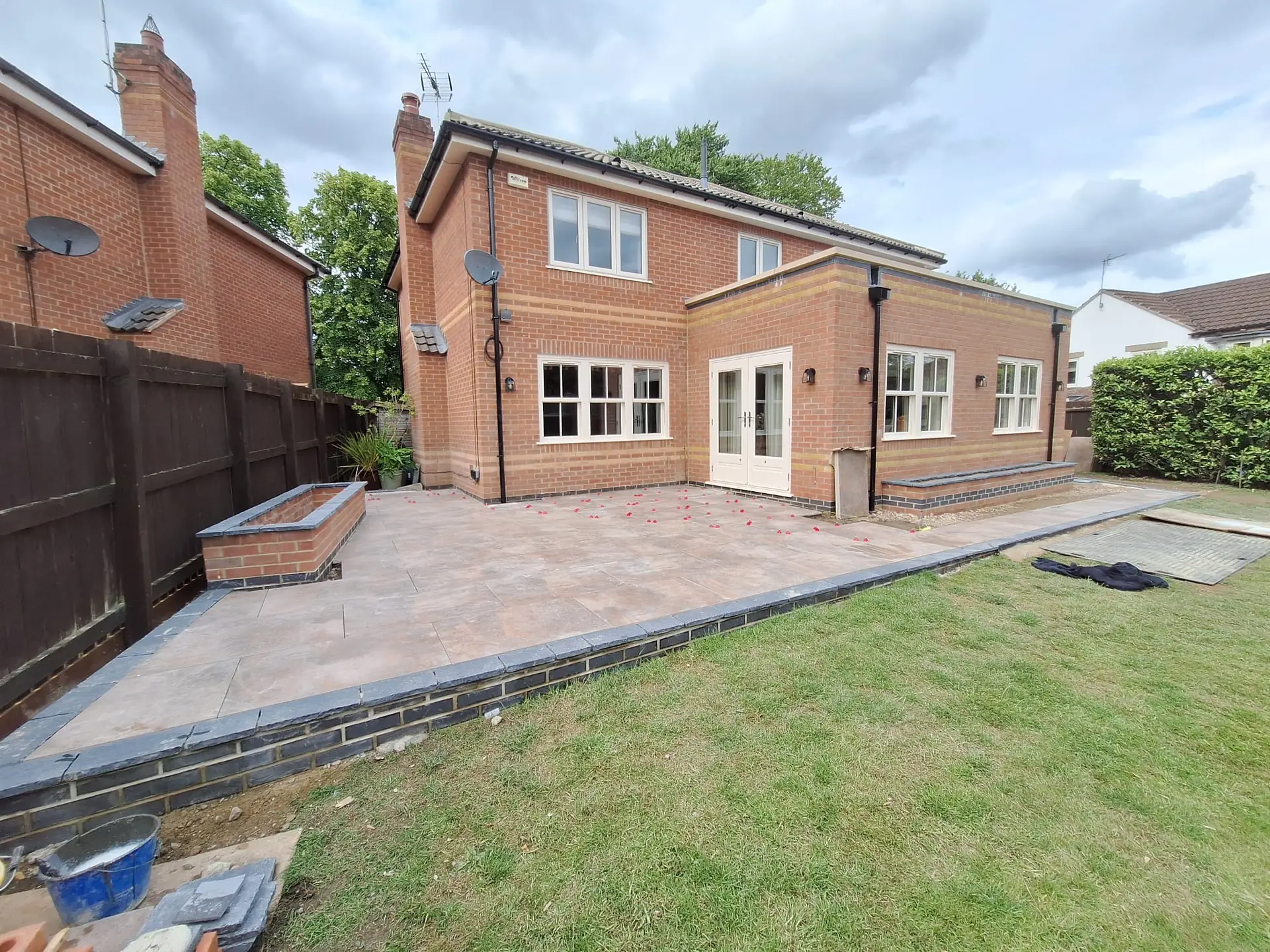 Sandstone patio around the back of a brick house