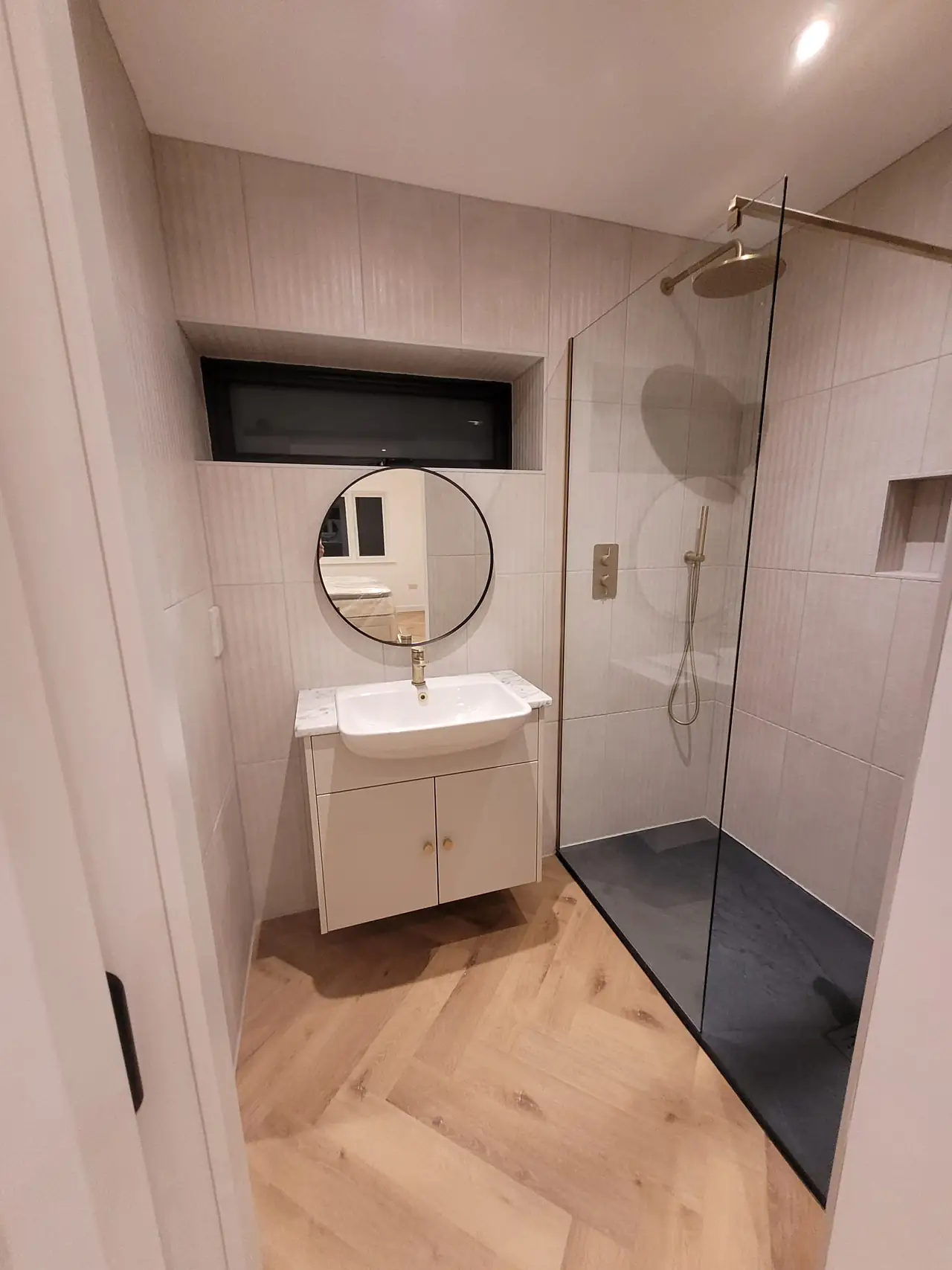Shower room with a round mirror in marble effect tiles