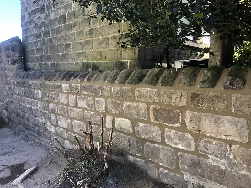 Stone boundary wall rebuilt in the original stone