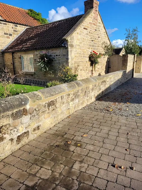 Stone cottage and boundary wall on a cobbled lane