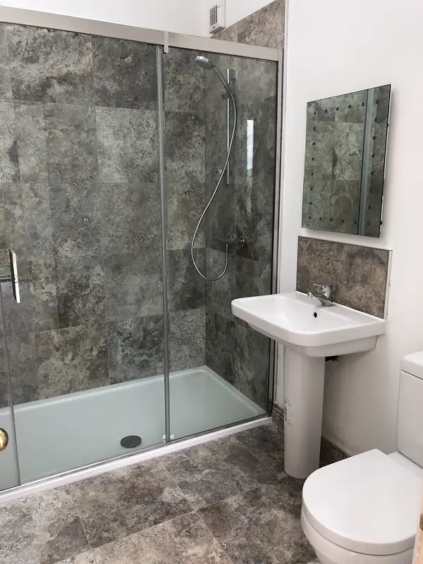 Stone tiled shower with a glass screen