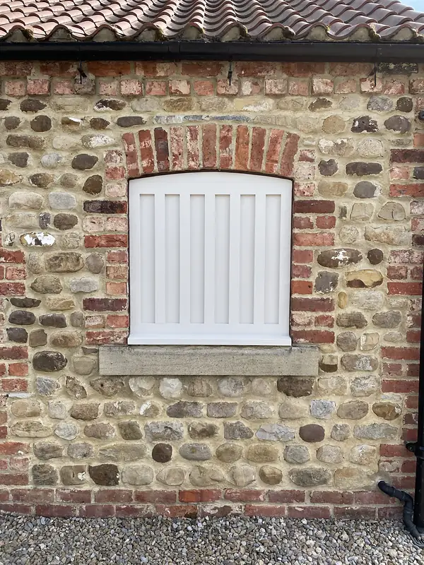 Window opening rebuilt in stone and brick with timber shutters